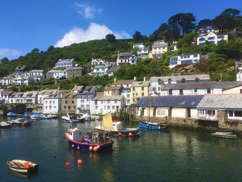 Boats moored on river by town against sky