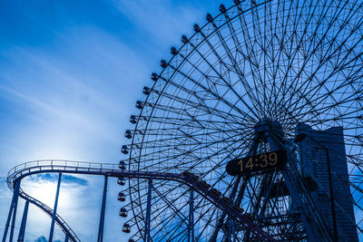 Low angle view of ferris wheel against cloudy sky