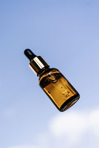 A brown bottle of serum against the sky.