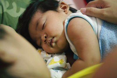 Midsection of woman with hand on boy sleeping at home