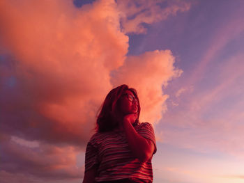 Woman standing on field against sky during sunset