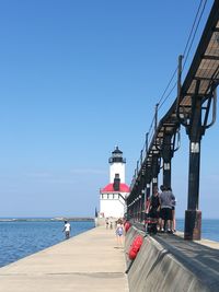 People on pier by sea against clear blue sky lake michigan