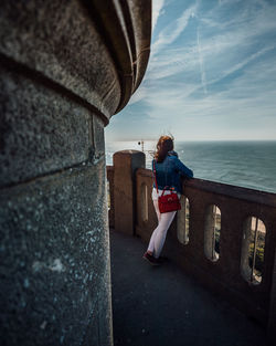 Woman standing by sea against sky