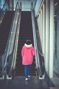 Rear view of woman walking on escalator