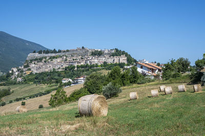 Houses on field against clear blue sky