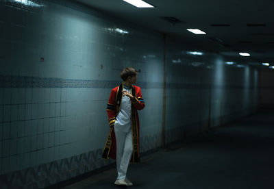 Side view of man standing in illuminated subway