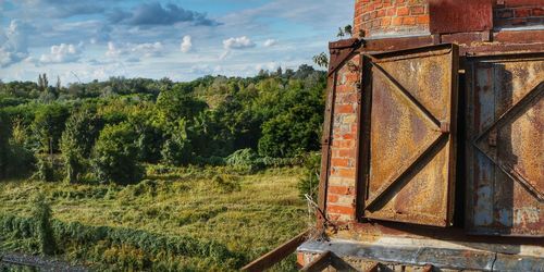 Rusty metallic structure on field against sky