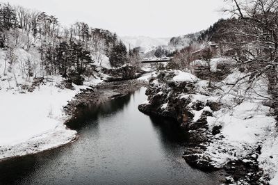 River amidst trees against sky during winter