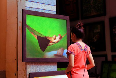 Rear view of woman looking at painting