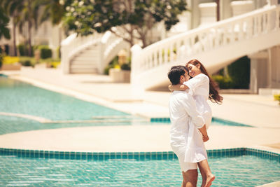 Full length of couple standing by swimming pool