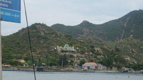 View of buildings by mountain against cloudy sky