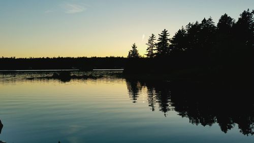 Reflection of trees in lake at sunset