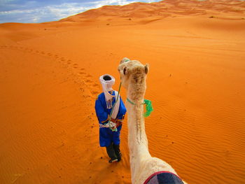 Man with camel standing on sand