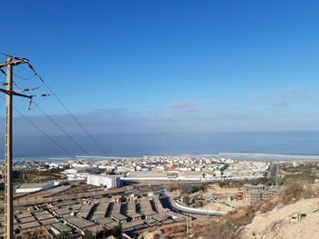 High angle view of buildings and sea against blue sky