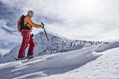 Woman skiing on snowcapped mountain against sky