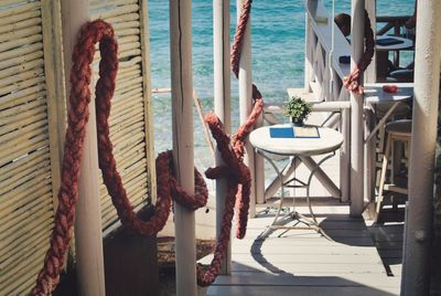 Young woman sitting on chair at table by sea