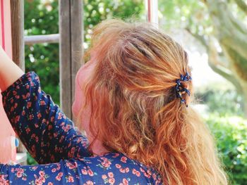 Side view close-up of young woman with long blond hair in yard