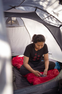 Woman in tent using cell phone