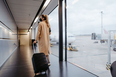 Rear view of woman walking with suitcase at airport