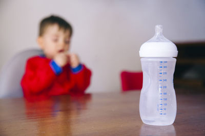 Close-up of milk bottle on table with boy in background