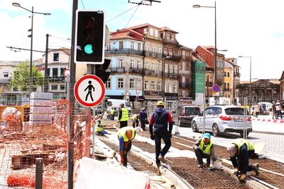 Men working on road against buildings during sunny day