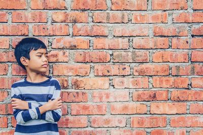 Full length of boy standing against red brick wall