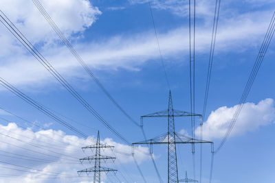 Low angle view of electricity pylon against blue sky