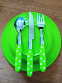 High angle view of green plate with cutlery on table