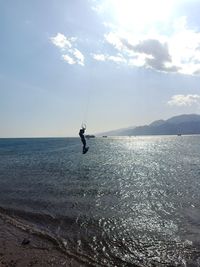 Man fishing in sea against sky