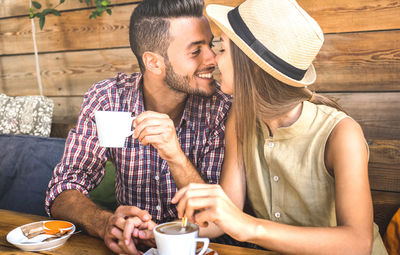 Young couple kissing while having coffee in cafe