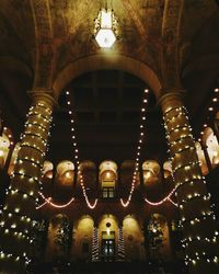 Low angle view of illuminated lighting equipment hanging against sky