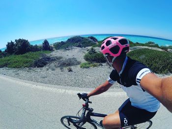 Man riding bicycle on road against sky