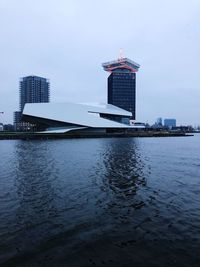 Modern building by sea against sky in city