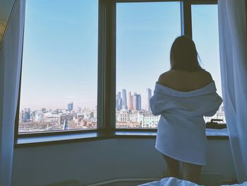 Rear view of woman looking through window