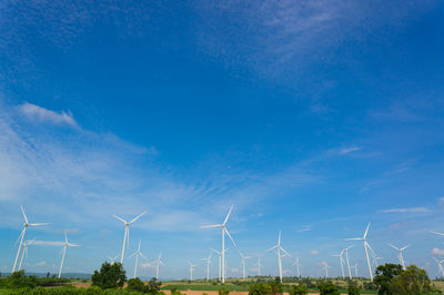 Wind turbines on field against sky