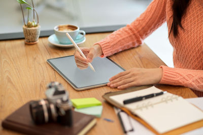 Midsection of woman using smart phone on table