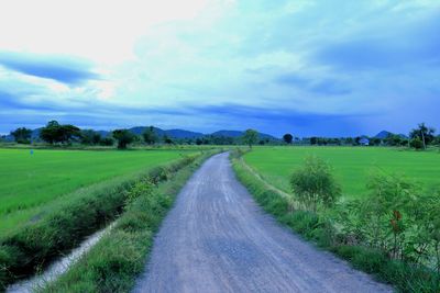 Road amidst field against sky