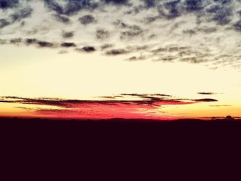 Silhouette landscape against dramatic sky during sunset