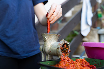 Midsection of person preparing meat on barbecue grill