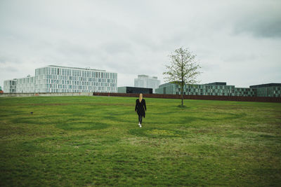 Rear view of man walking on field against sky