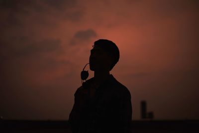 Silhouette man standing against orange sky