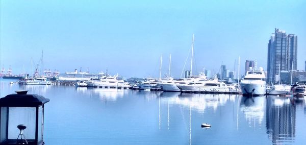 Sailboats moored in harbor against clear blue sky