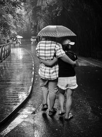 Rear view of mother and daughter in rain