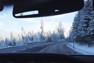 Road amidst trees seen through car windshield