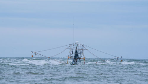 Shrimpboat sinking on sea against sky