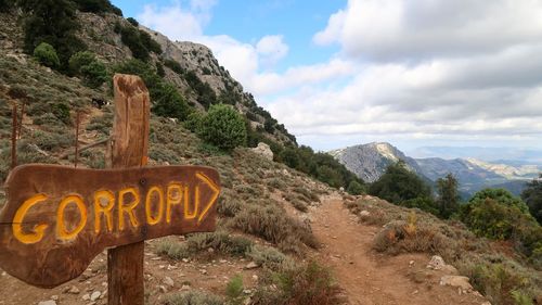 Information sign on mountain against sky