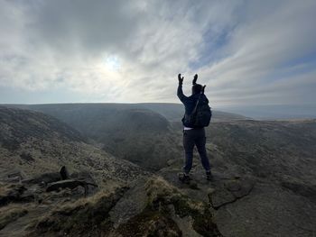 Rear view of man standing on mountain against sky