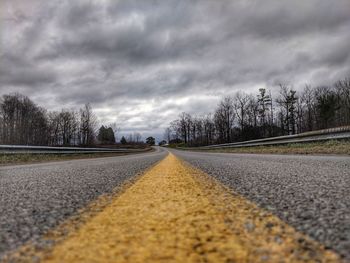 Surface level of empty road against cloudy sky