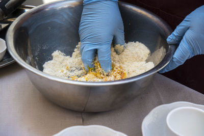 Cropped hands preparing food in bowl on table