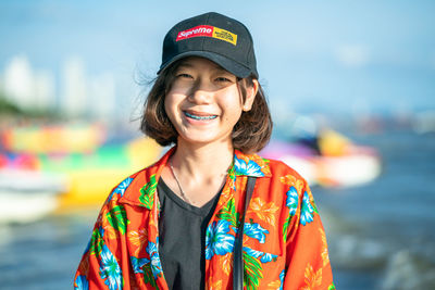 Portrait of smiling young man standing against water
